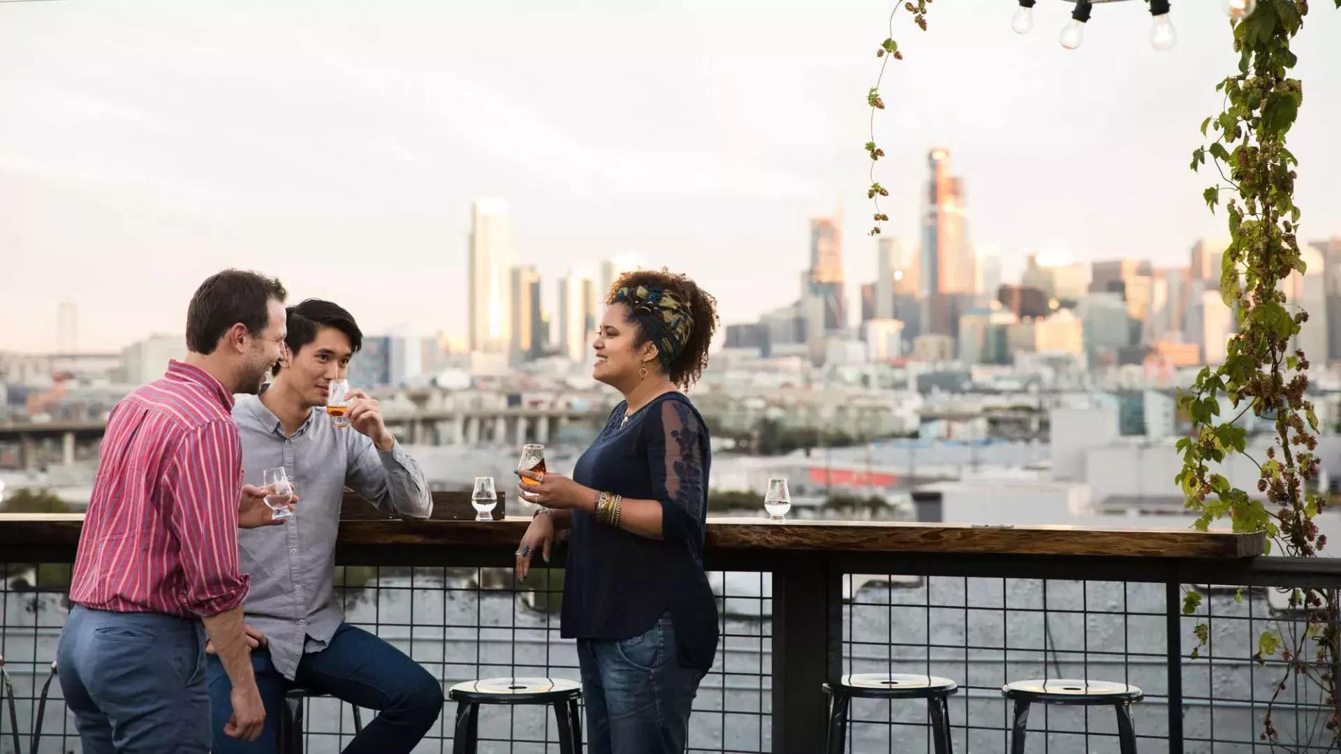 三个人聚在加州贝博体彩app的锚定公司屋顶甲板上的一张露天桌子旁。。